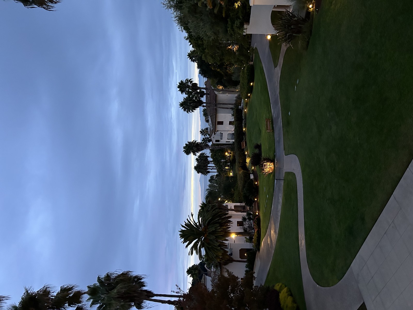 Palm-lined resort grounds at dusk, lit pathways winding between buildings.